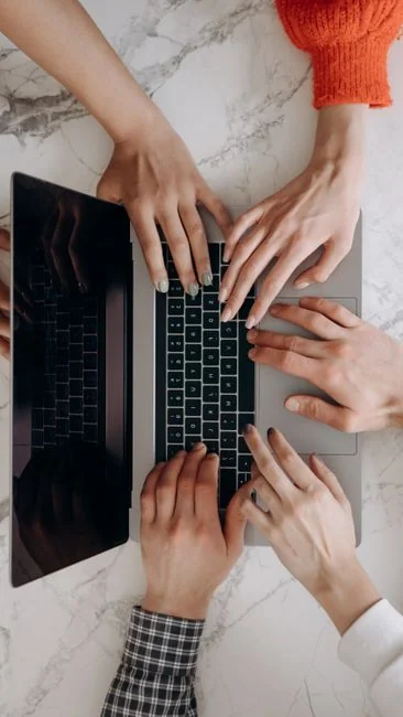 A diverse team collaborating on digital marketing strategies at a desk, using laptops and tablets.