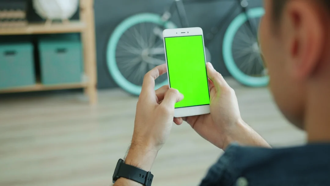 Person analyzes stock data with a smartphone and laptop, indoors.